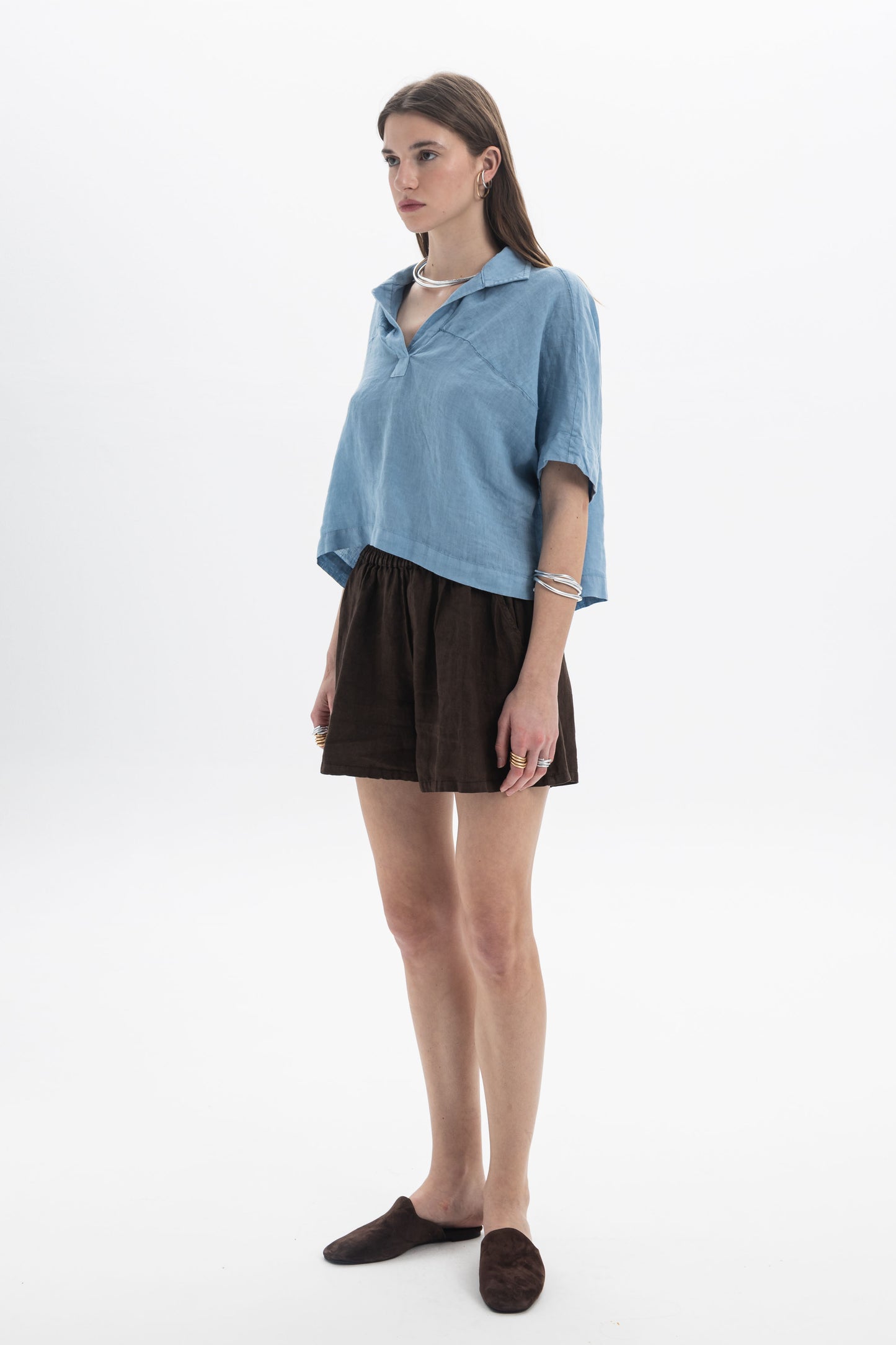 Model wearing a Linen Polo Top with relaxed silhouette and soft collar, paired with brown shorts.