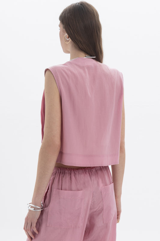 Back view of a woman wearing a Pleated Cropped Sleeveless Top in dusty pink, showcasing its modern silhouette.