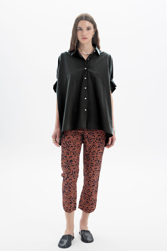 Black and Black oversized short sleeve button-up shirt displayed on a hanger, featuring a relaxed fit and classic collar.