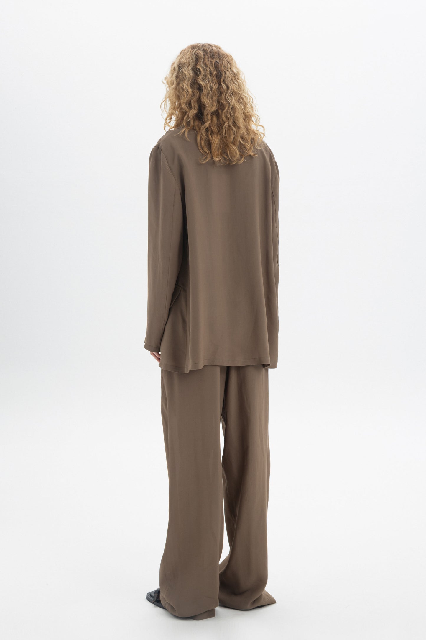 Fluid Tailored Trousers shown from the back, featuring a relaxed fit and soft drape, styled with a matching top.