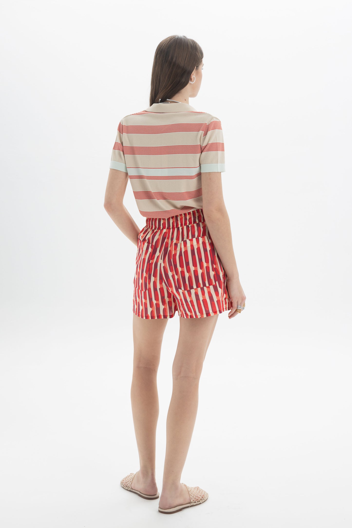 Model wearing a Striped Knit Polo with red and beige horizontal stripes, paired with patterned shorts.