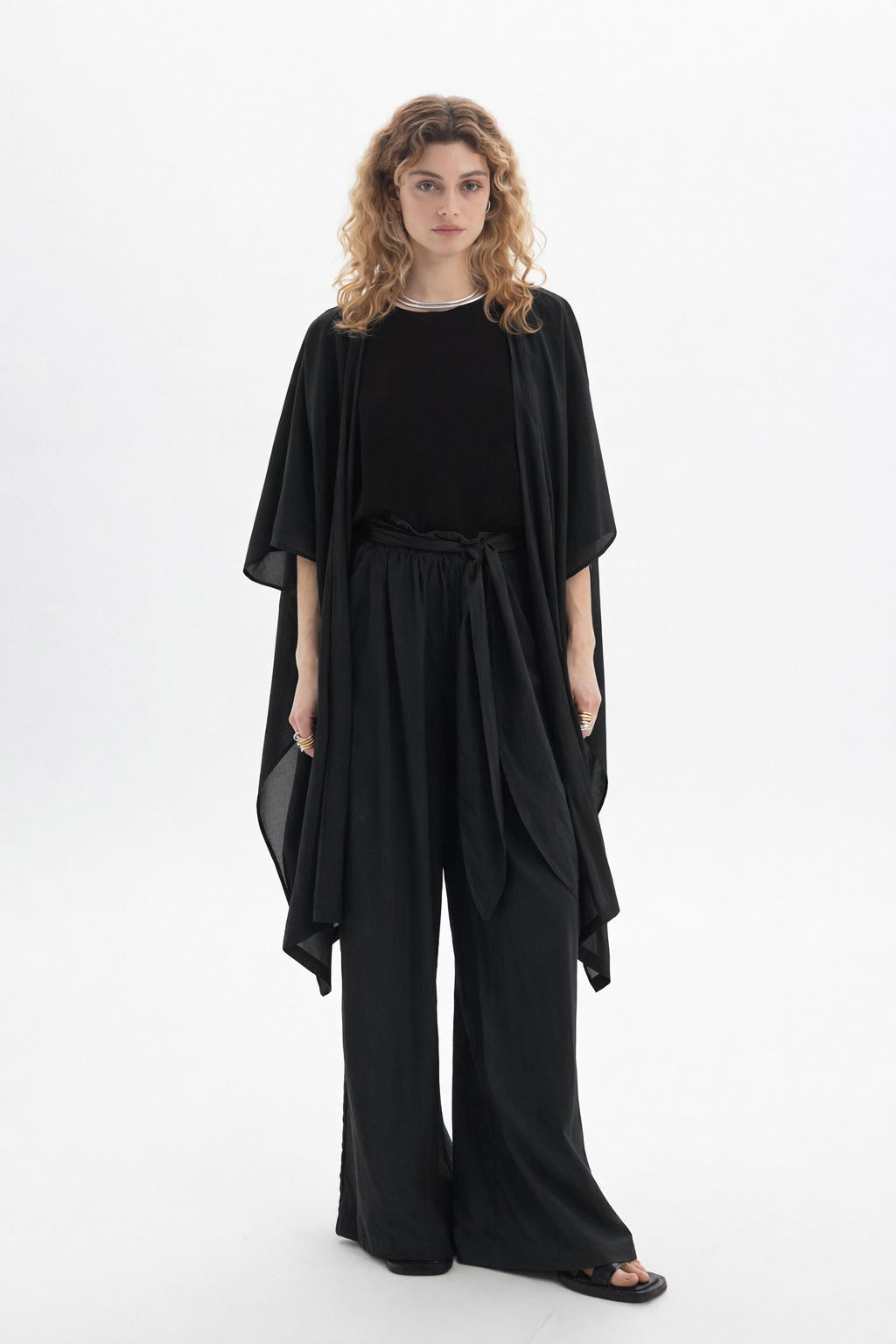 Model wearing a sheer kimono with wide sleeves over a black outfit, showcasing its fluid silhouette.