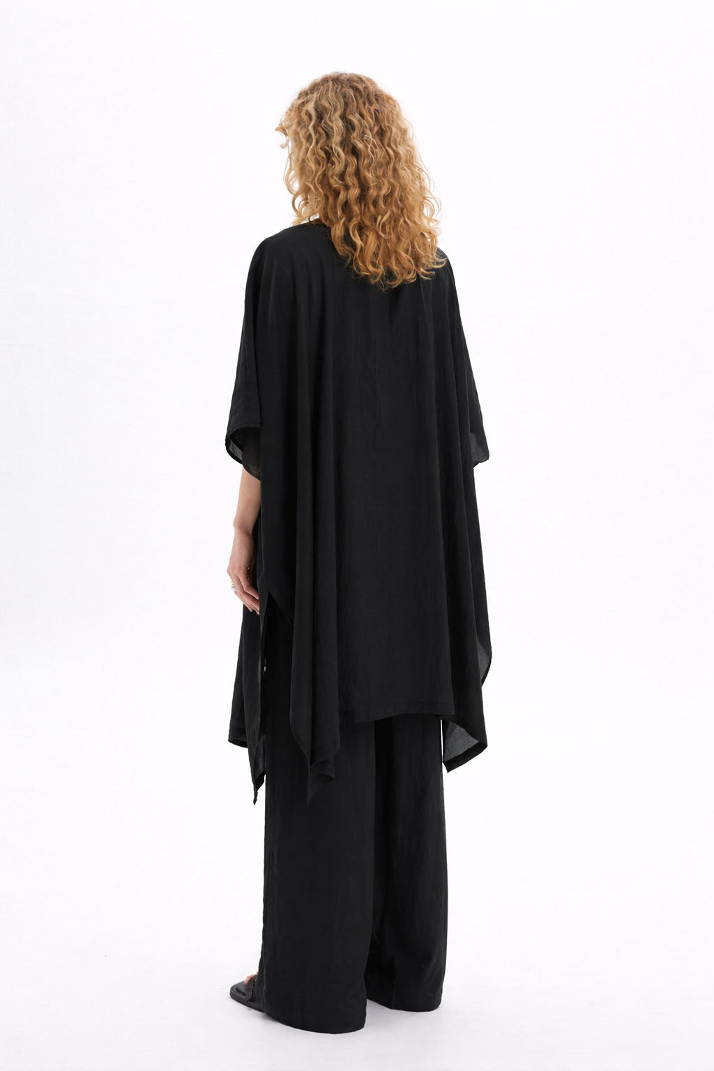 Back view of a woman wearing a black sheer kimono with wide sleeves and a relaxed drape.