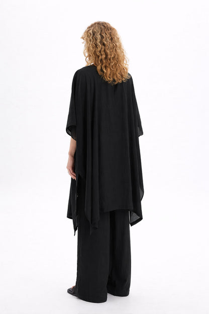 Back view of a woman wearing a black sheer kimono with wide sleeves and a relaxed drape.