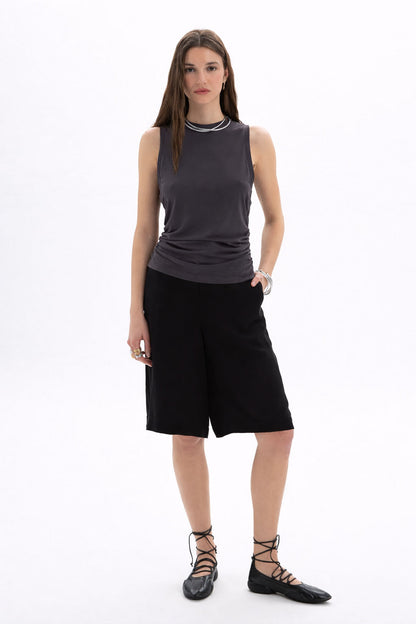 Model wearing a Ruched Sleeveless Top with side ruching and black shorts, showcasing contemporary style and refinement.