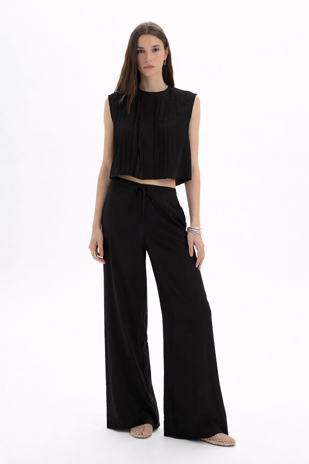Model wearing a Pleated Cropped Sleeveless Top paired with wide-leg trousers, showcasing a modern silhouette.