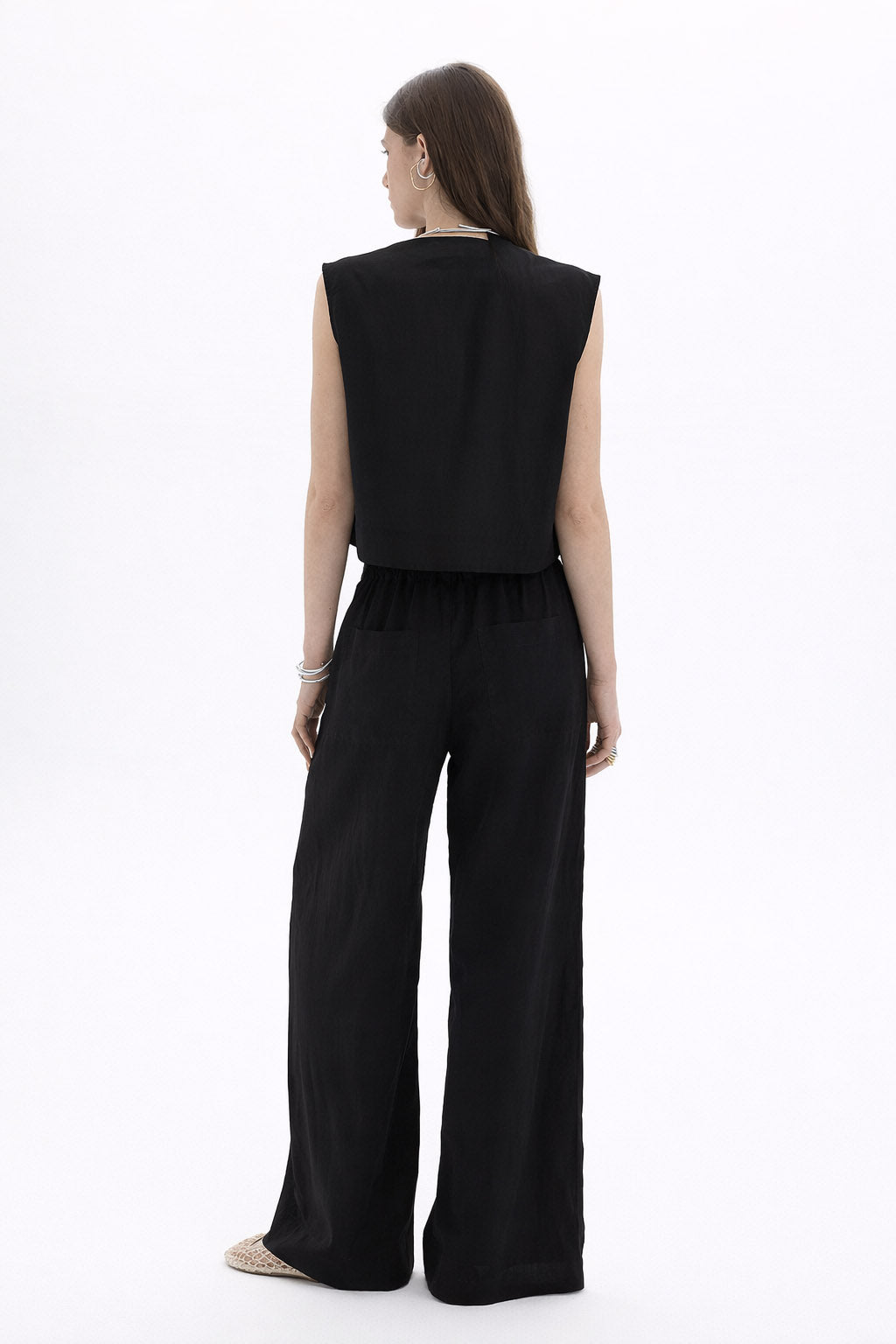 Back view of a model wearing a Pleated Cropped Sleeveless Top paired with wide-leg trousers.