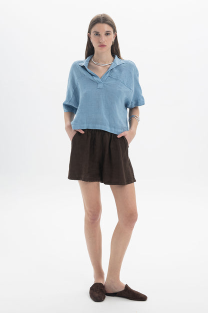 Woman wearing Linen Shorts paired with a blue linen top, showcasing a relaxed summer look.