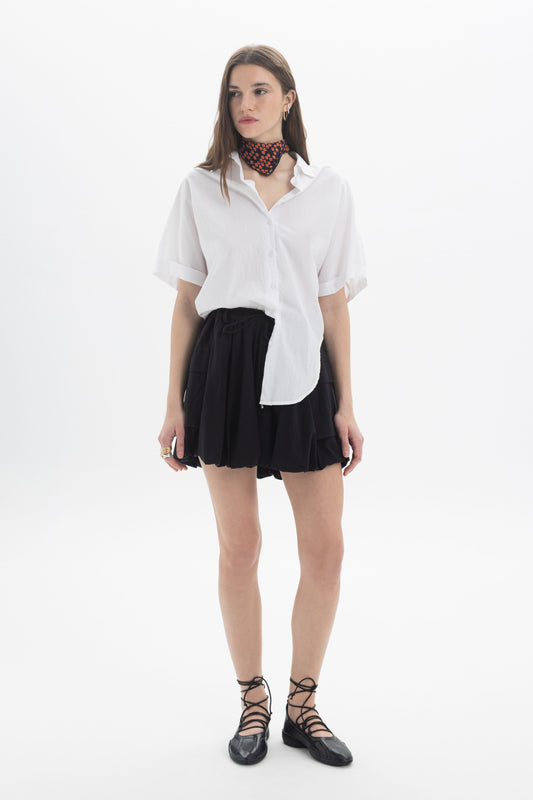 Model wearing a Balloon Mini Skort with a voluminous silhouette and a white shirt.