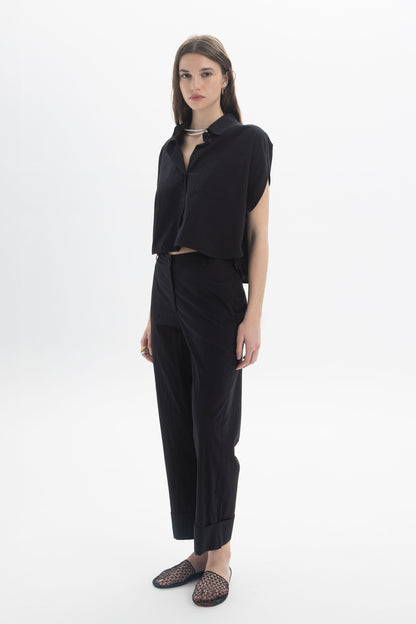 Cropped Button Shirt modeled with black pants, featuring a relaxed fit, classic collar, and short cap sleeves.