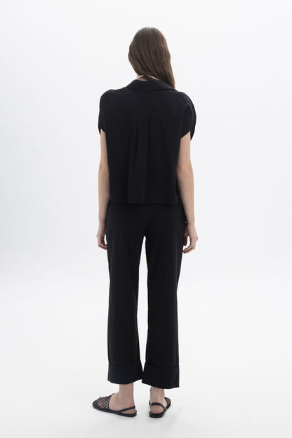 Back view of a model wearing a Cropped Button Shirt paired with black pants, showcasing modern summer style.