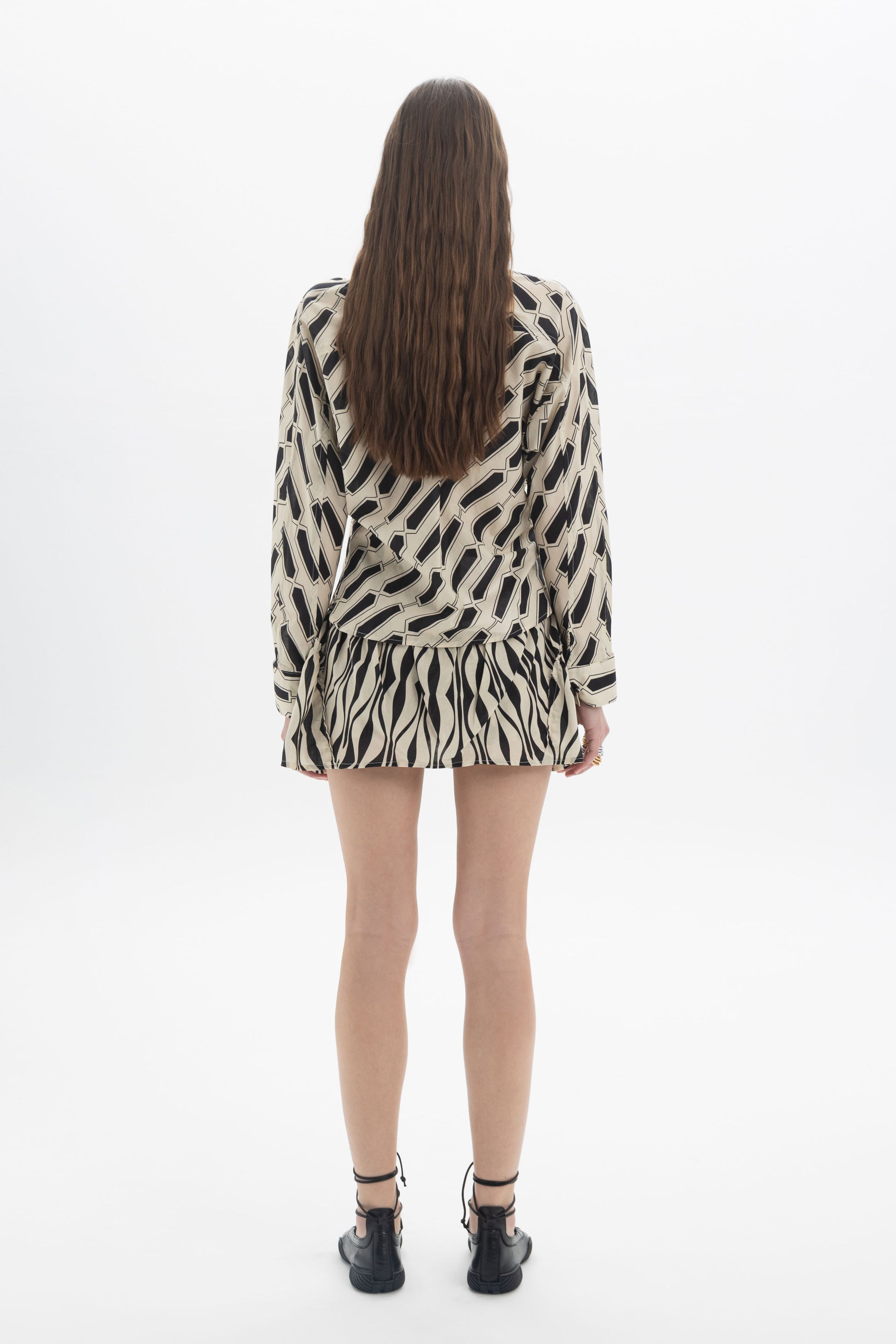 Back view of a model wearing a Ruffle Hem Skort with zebra-inspired print and a gathered ruffle hem.