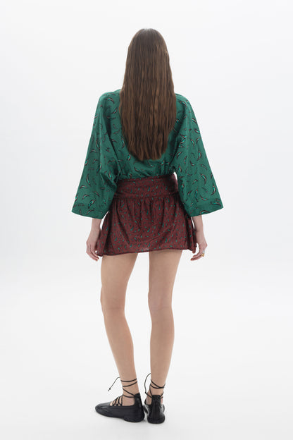 Back view of a model wearing a relaxed three-quarter sleeves shirt with a pattern and a skirt.