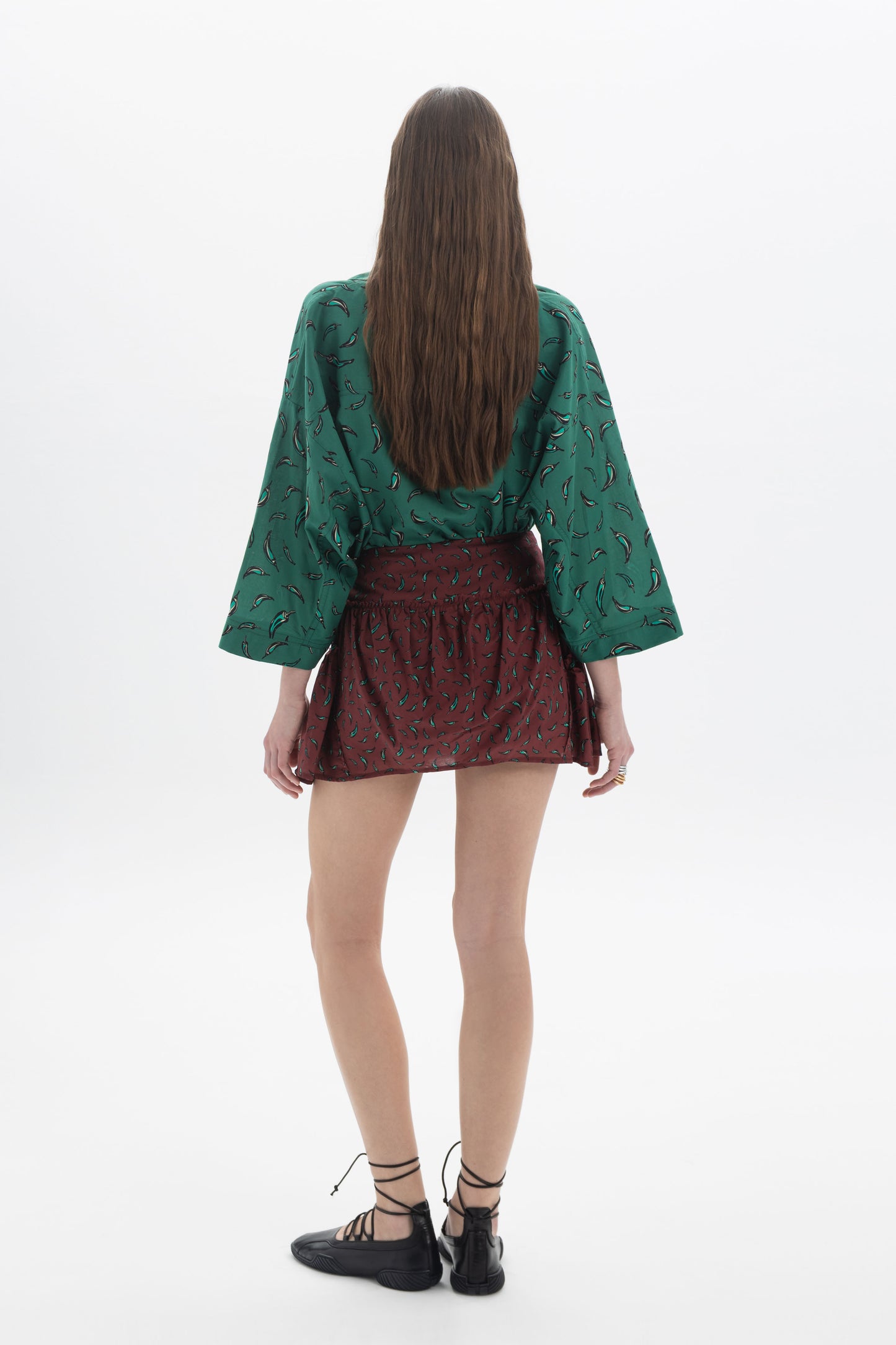 Model wearing a green top and Mini Skort with an allover print, showcasing a structured silhouette.