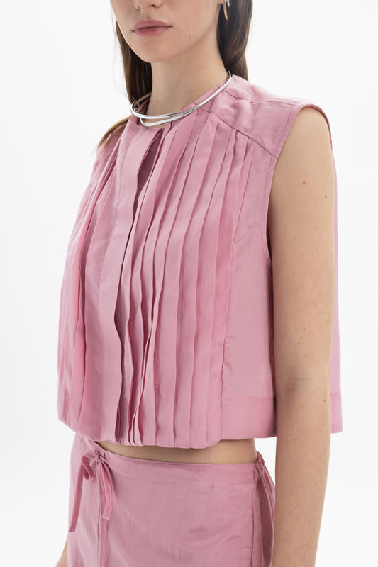 Pleated Cropped Sleeveless Top in soft pink with pleats and round neckline, styled with relaxed trousers.