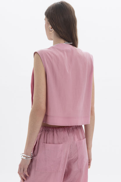 Back view of a woman wearing a Pleated Cropped Sleeveless Top in dusty pink, showcasing its modern silhouette.