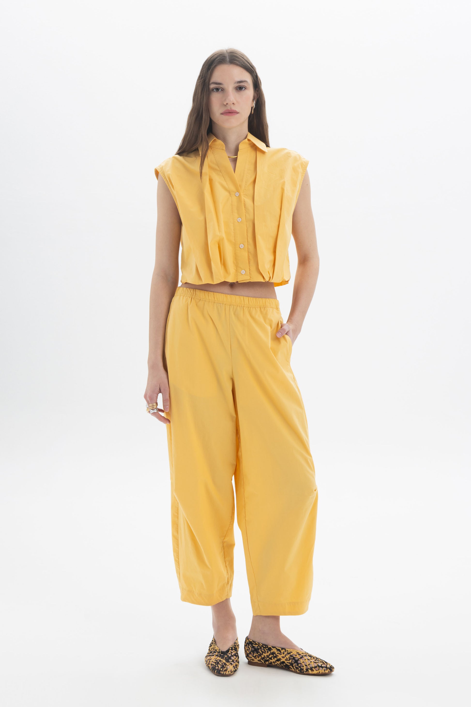 Cropped Sleeveless Shirt styled with yellow wide-leg pants, showcasing a modern and effortless outfit.