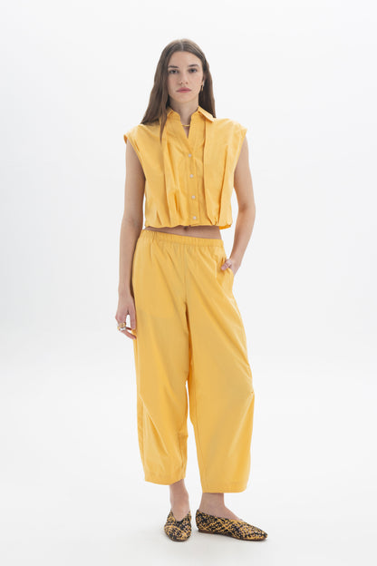 Cropped Sleeveless Shirt styled with yellow wide-leg pants, showcasing a modern and effortless outfit.