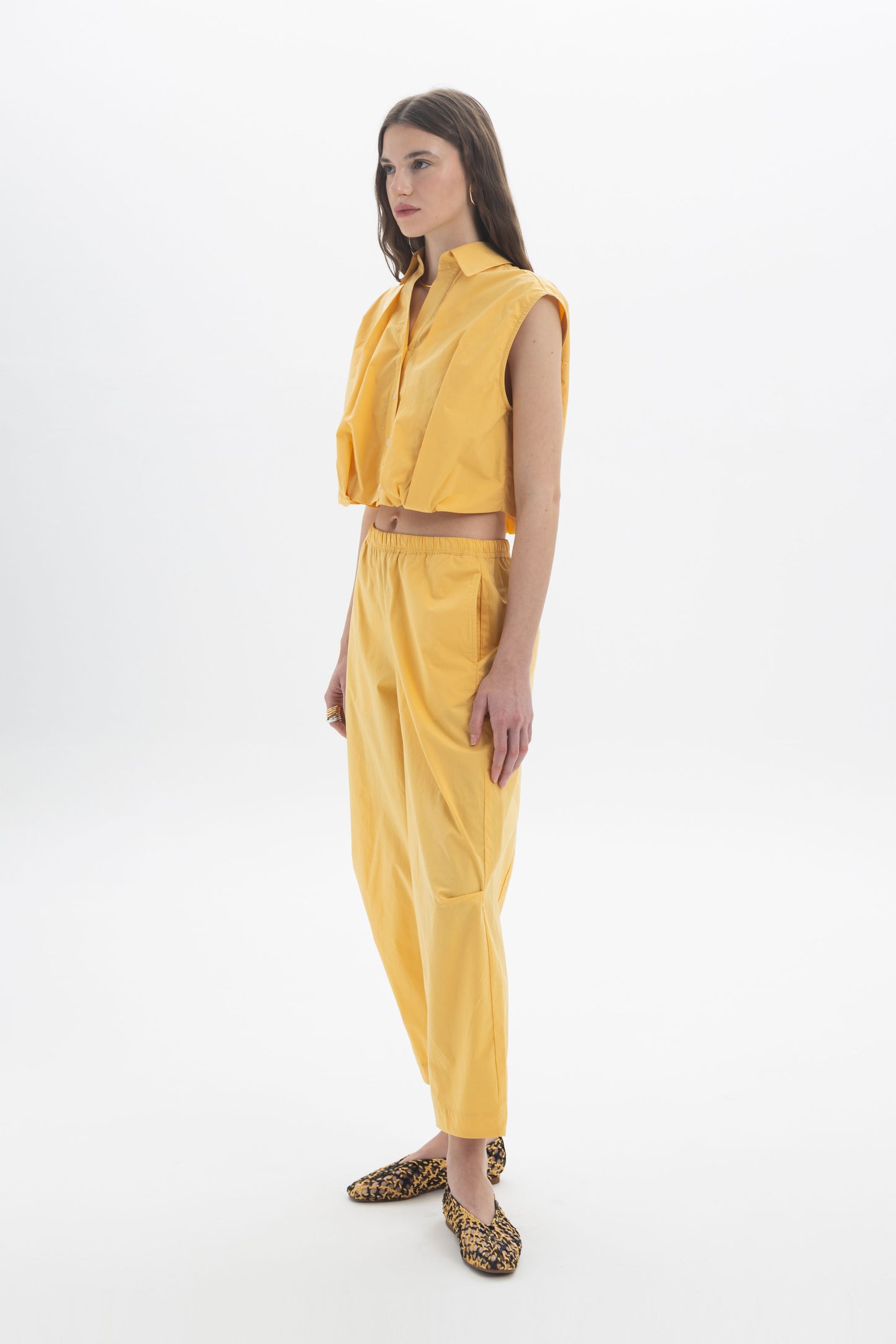 Cropped Sleeveless Shirt in yellow with classic collar and front button closure, featuring a rounded silhouette at the waist.