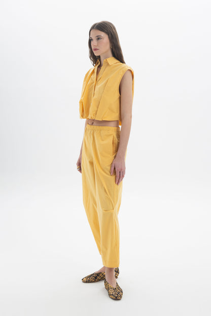 Cropped Sleeveless Shirt in yellow with classic collar and front button closure, featuring a rounded silhouette at the waist.