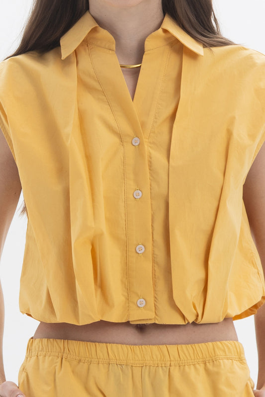 Cropped Sleeveless Shirt in yellow with classic collar and button closure, featuring soft volume and rounded silhouette at waist.