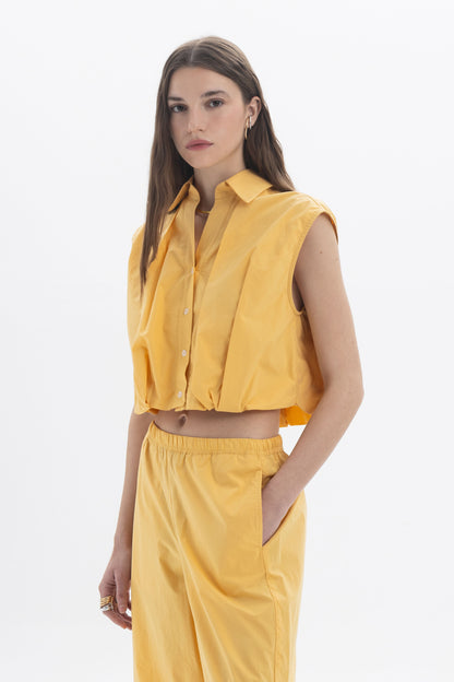 Cropped Sleeveless Shirt in yellow with classic collar and front button closure, styled for a modern look.