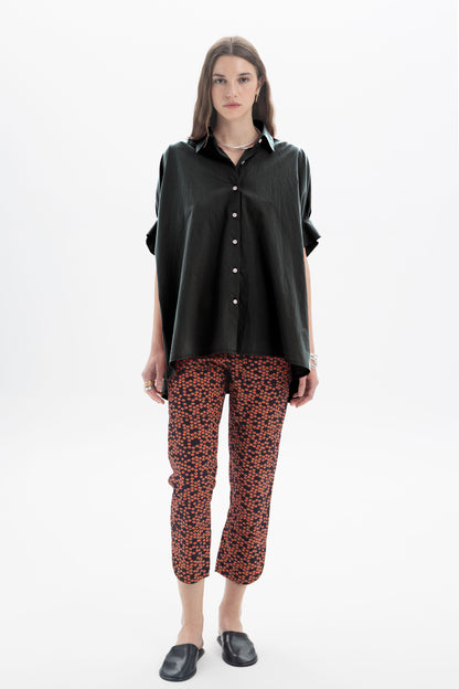 Black and Black oversized short sleeve button-up shirt displayed on a hanger, featuring a relaxed fit and classic collar.