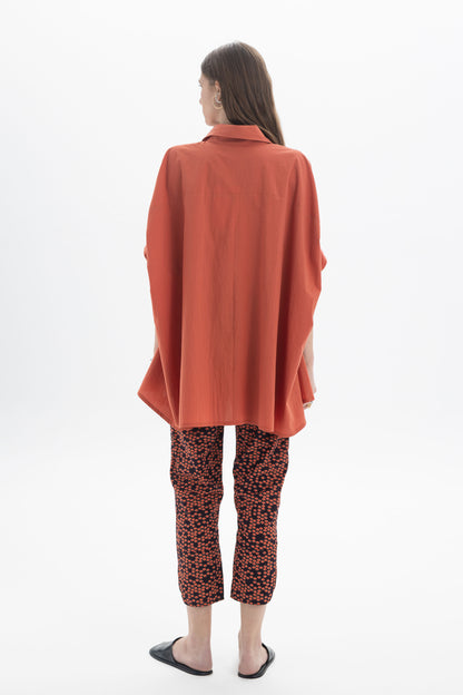Model wearing Cropped Printed Pants with a flowy orange top from the back view.