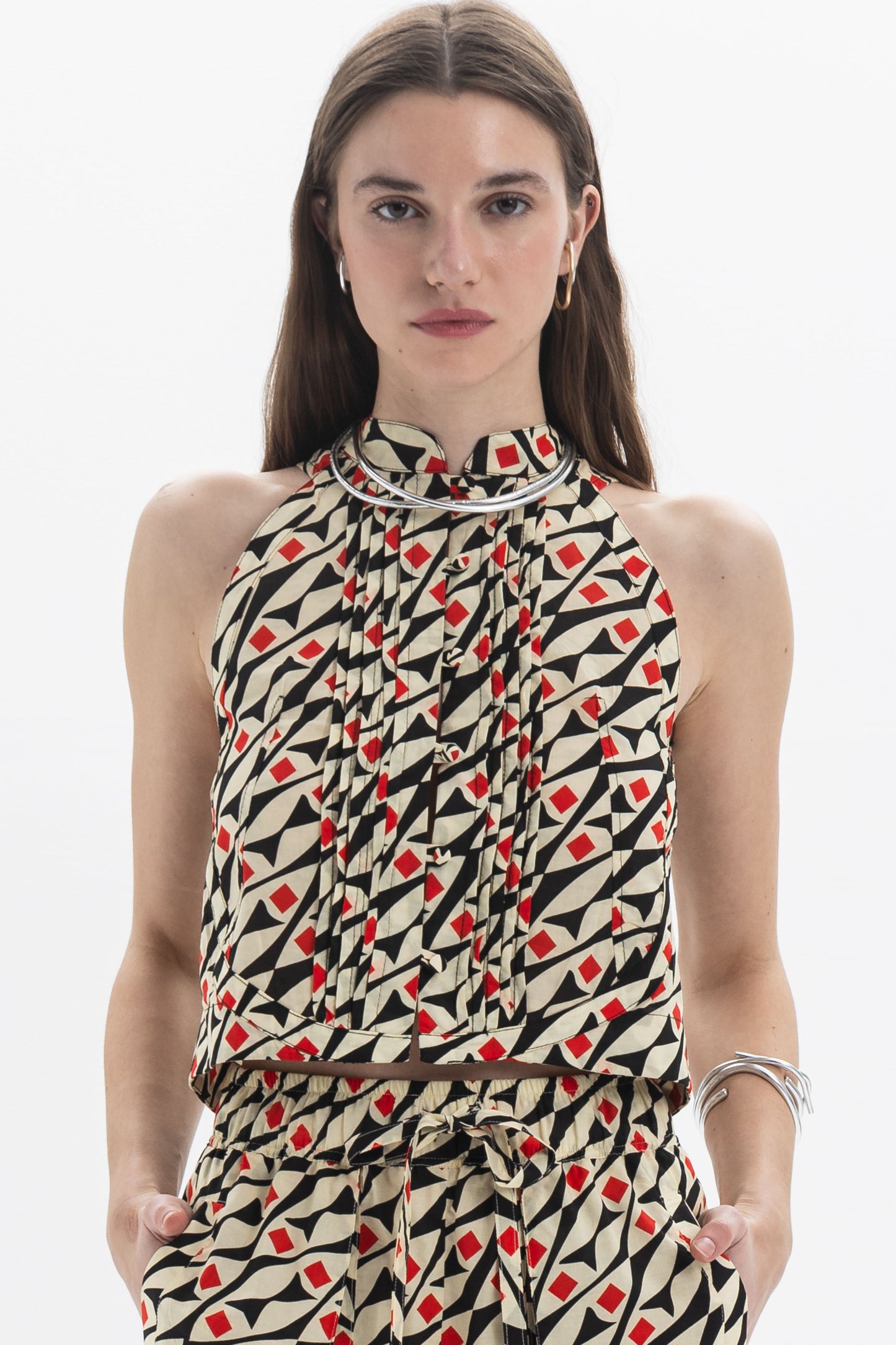 Model wearing a Pleated Halter Top with all-over graphic print and structured high neckline, showcasing soft pleating.