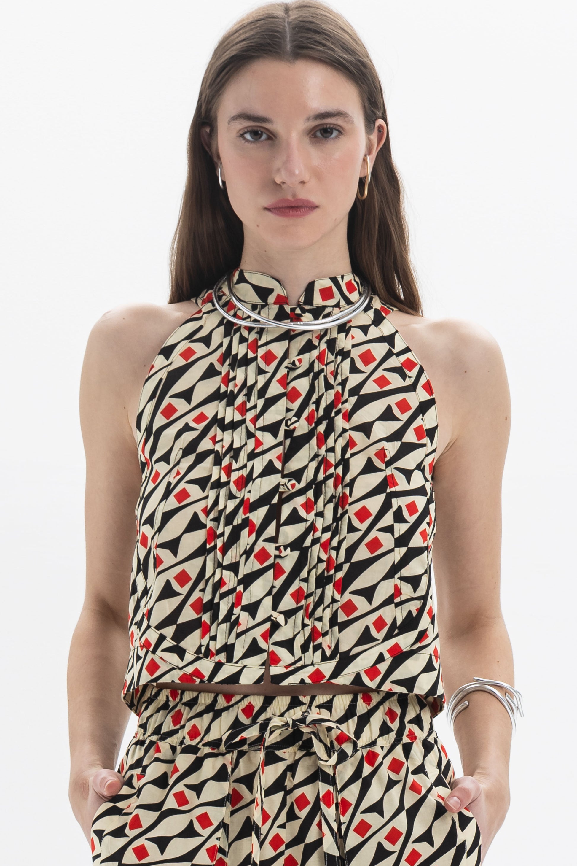Model wearing a Pleated Halter Top with all-over graphic print and structured high neckline, showcasing soft pleating.