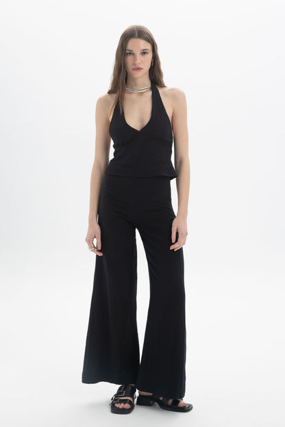 Halter Neck Fitted Top worn with flared trousers, showcasing a stylish look with a deep V neckline and open back.