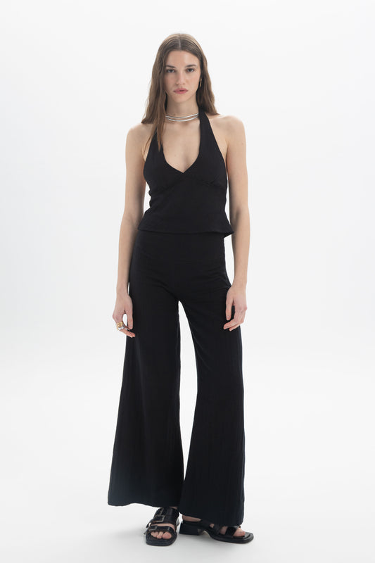 Halter Neck Fitted Top worn with flared trousers, showcasing a stylish look with a deep V neckline and open back.