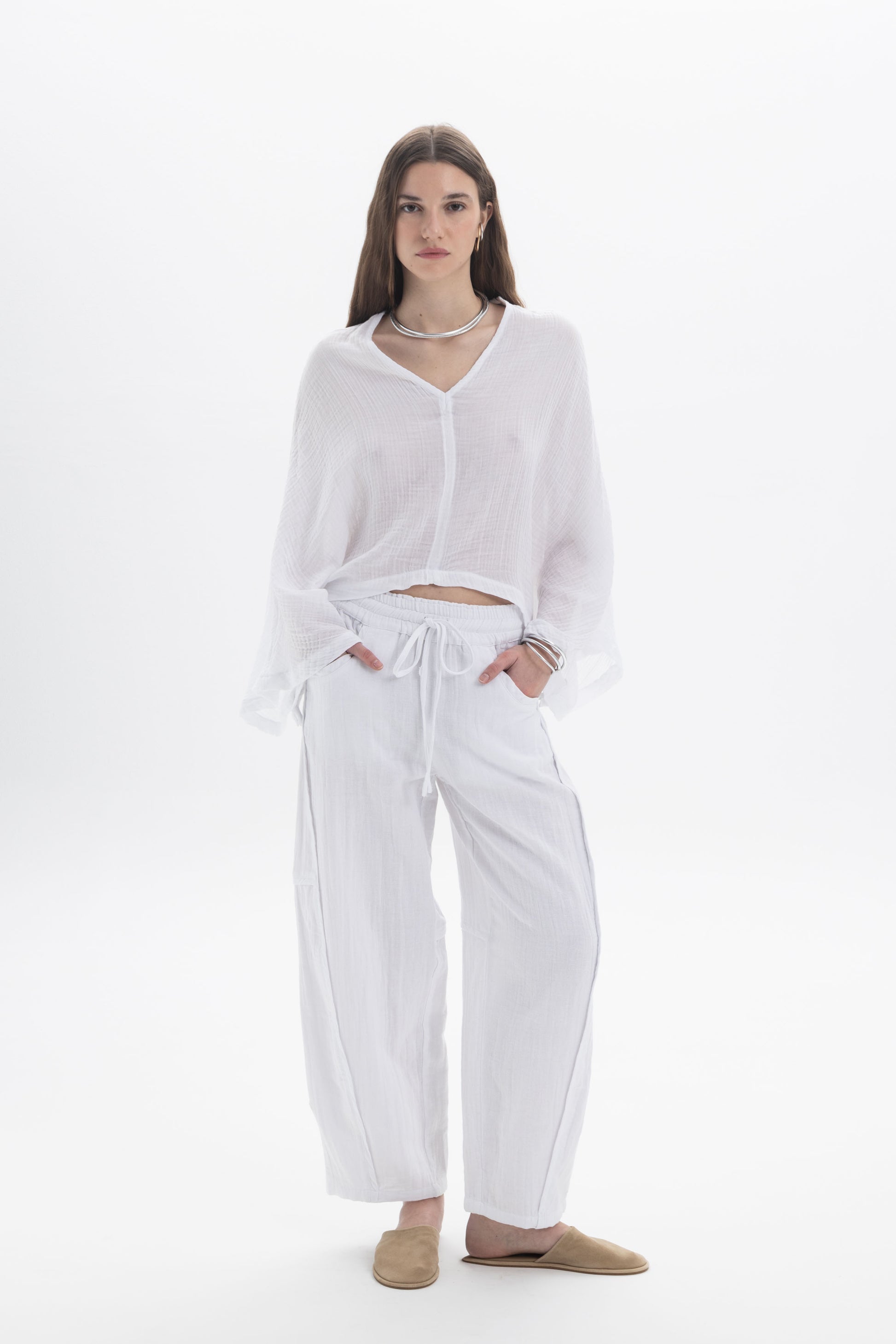 Model wearing a Sheer V-Neck Blouse with relaxed silhouette and flowing sleeves, styled with wide pants.
