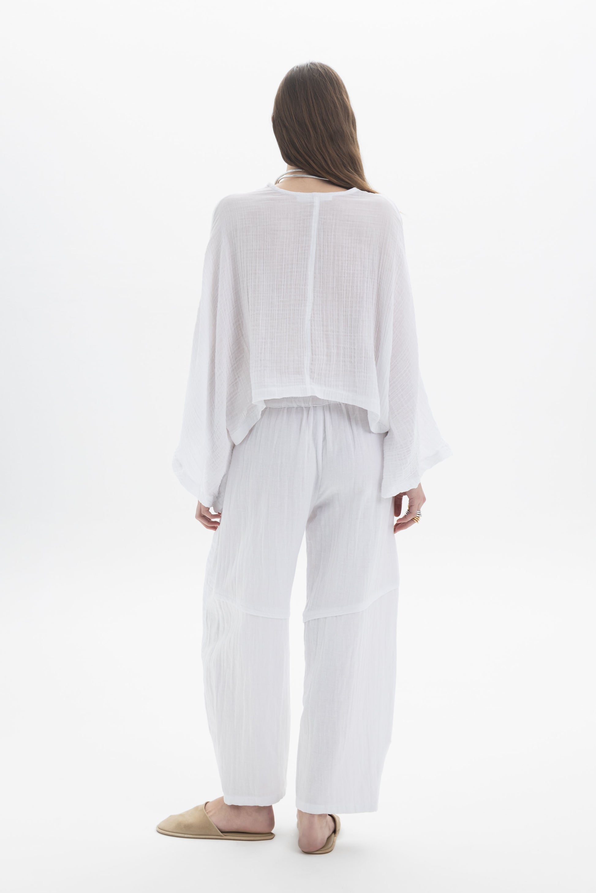 Back view of a woman wearing a Sheer V-Neck Blouse paired with wide flowing pants, styled for a relaxed look.