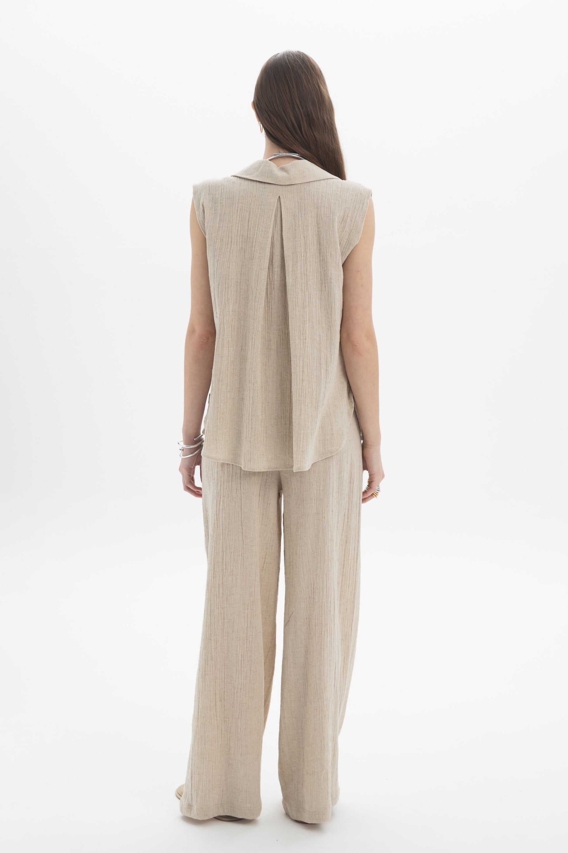 Back view of a model wearing a Sleeveless Textured Collar Blouse paired with wide-leg pants.