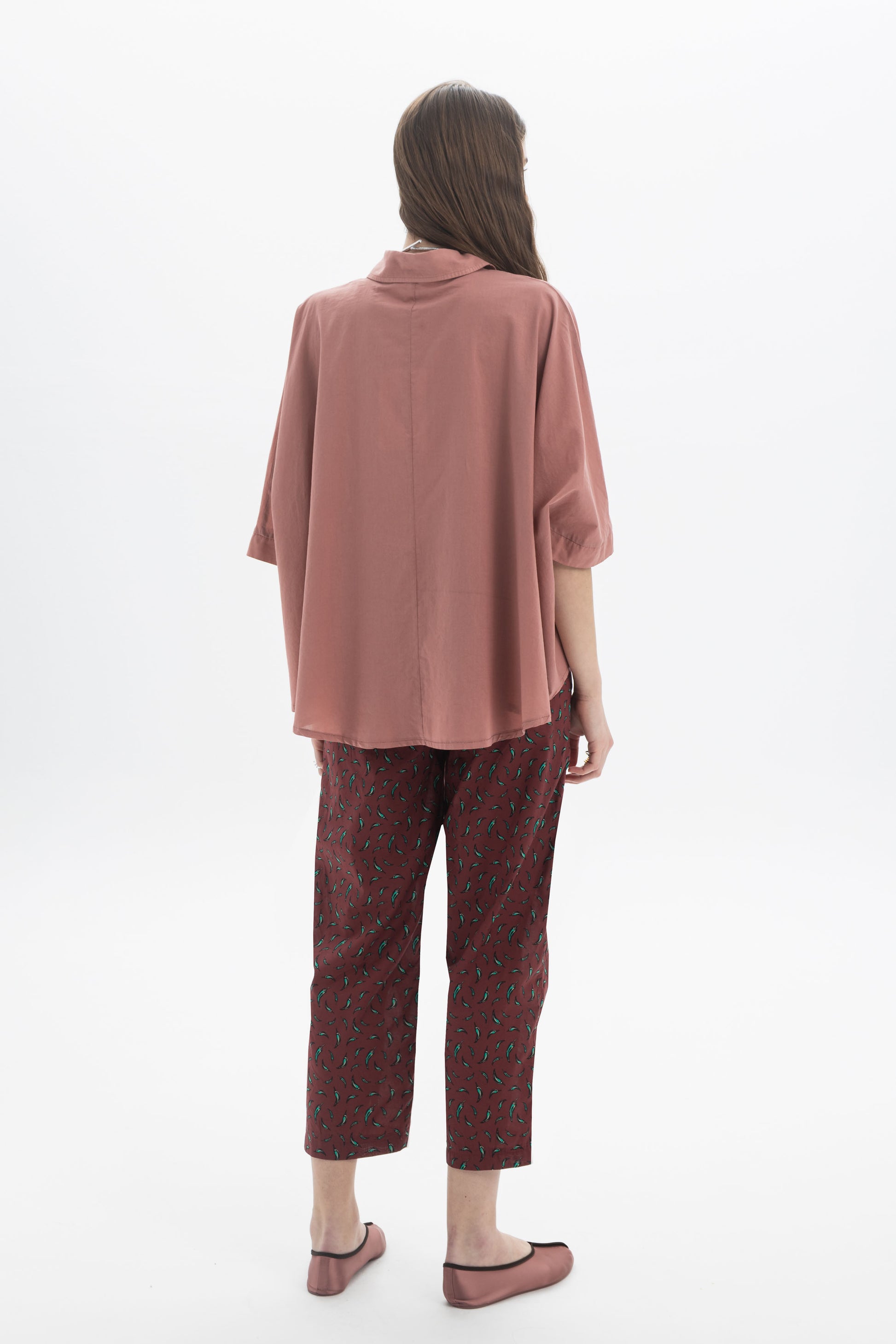 Back view of a model wearing an Oversized Short Sleeve Shirt with wide sleeves, complemented by patterned trousers.