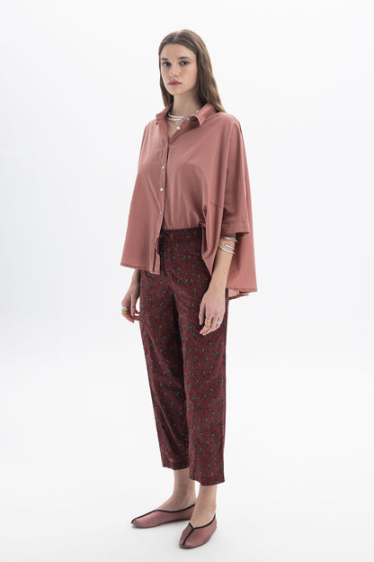 Model wearing an oversized short sleeve shirt in rose pink with wide short sleeves and floral pants.