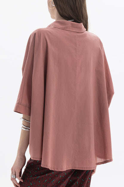 Back view of an Oversized Short Sleeve Shirt in a soft pink hue, highlighting its relaxed fit and wide short sleeves.