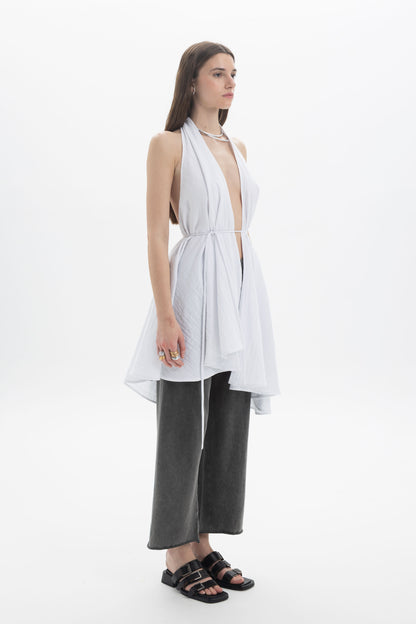 Longline Halter Top in white with a deep neckline and draped panels, styled with loose pants.