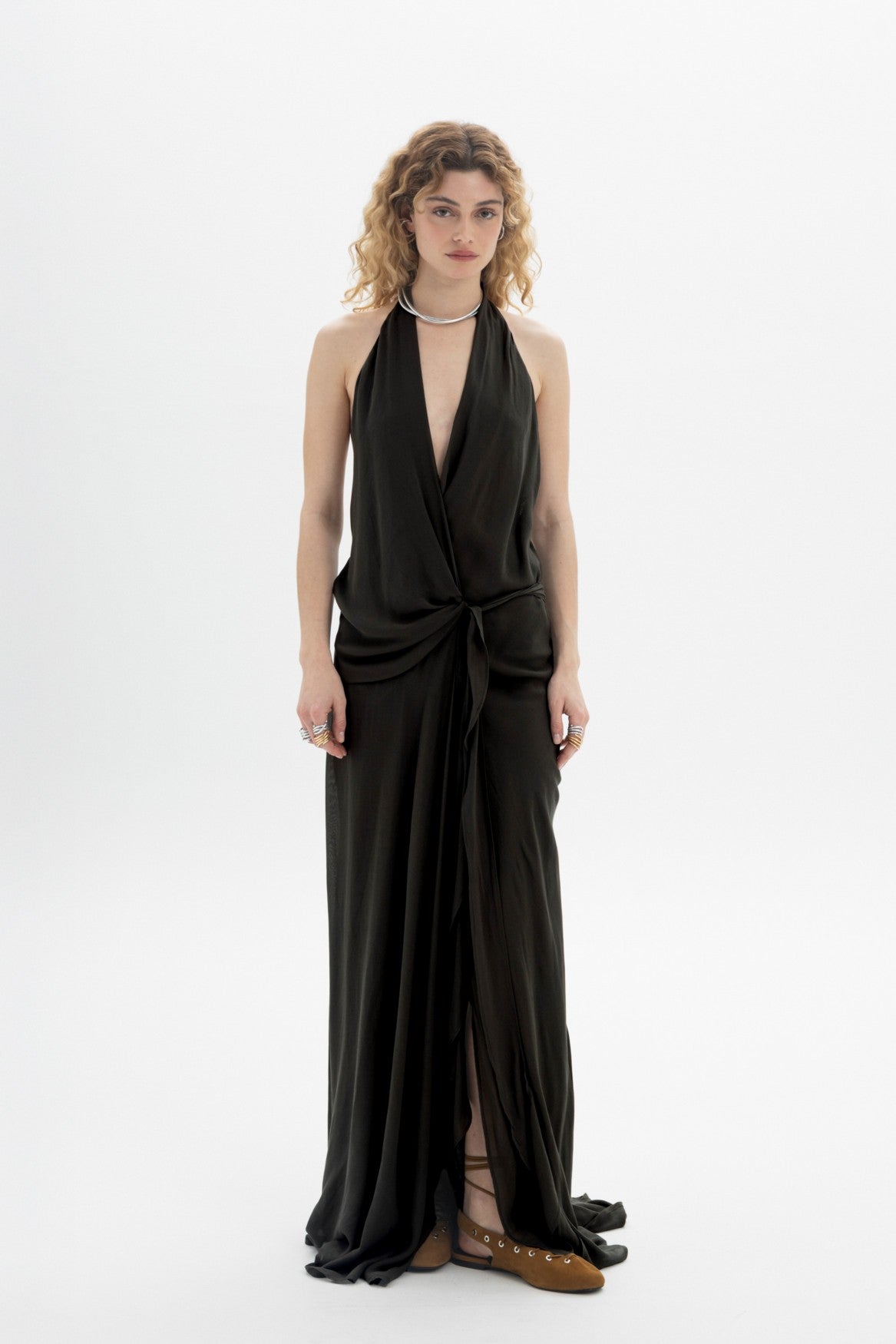 Black halter wrap maxi dress with deep neckline and open back, featuring wrap-style front and front slit.