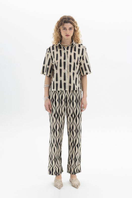 Model showcasing Abstract Straight Trousers made of cotton with an abstract print, featuring an elastic waistband and side pockets.