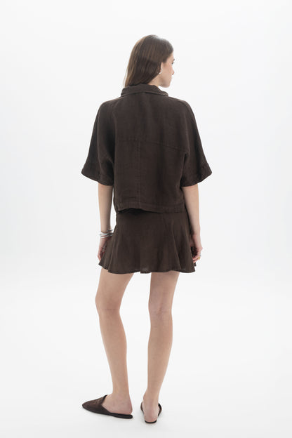 Back view of a model wearing a Linen Polo Top with a relaxed fit and short sleeves, perfect for summer style.