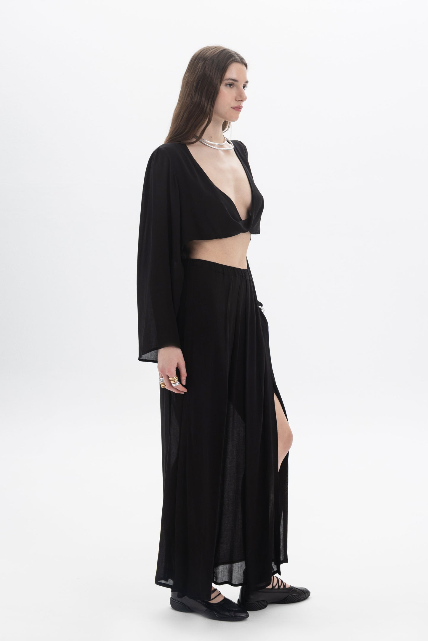 Model showcasing a Draped Cropped Long Sleeve Top with a deep V neckline and flowing silhouette.