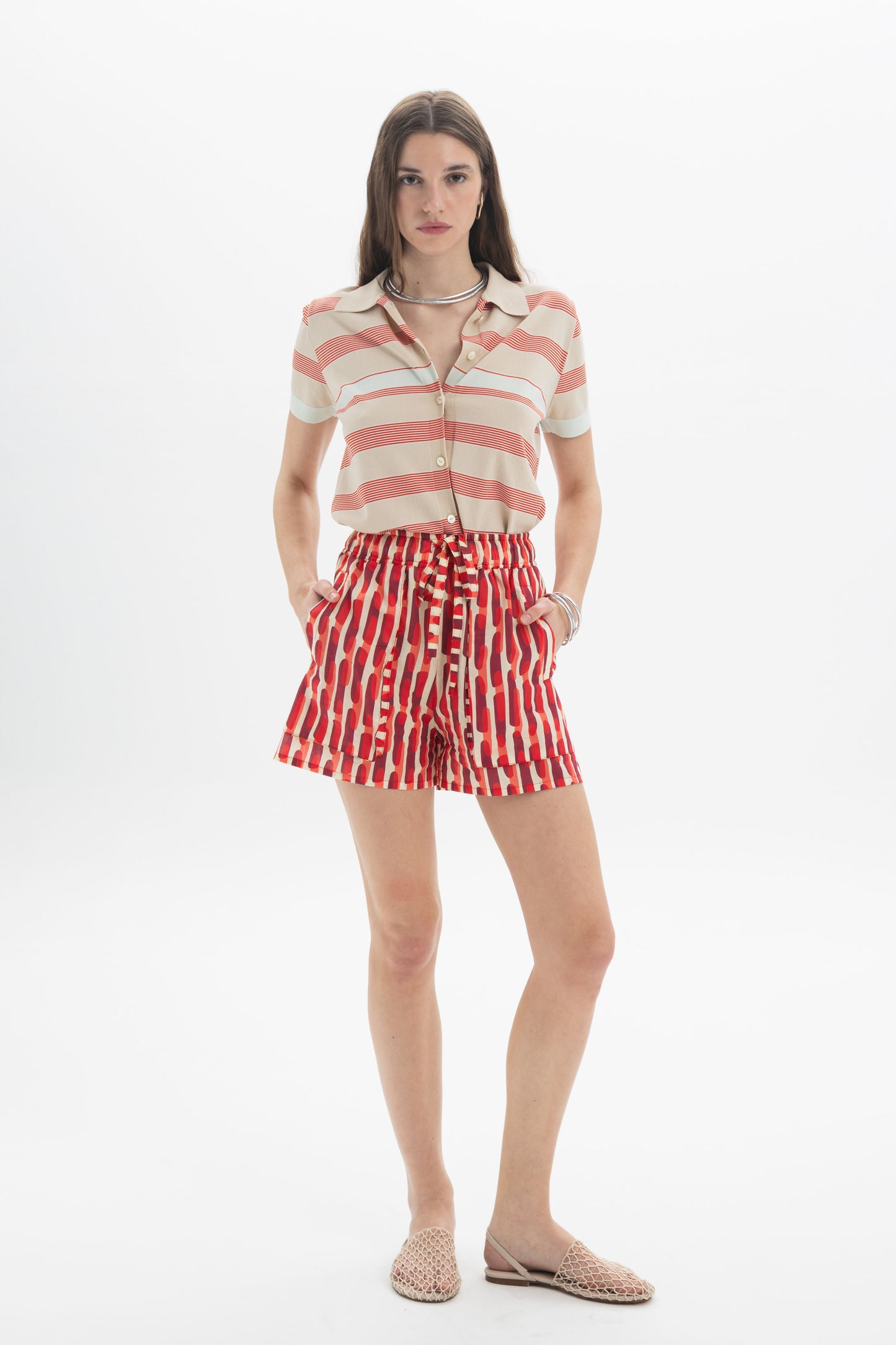 Model wearing a Striped Knit Polo with red and cream stripes, paired with stylish shorts for a casual summer look.