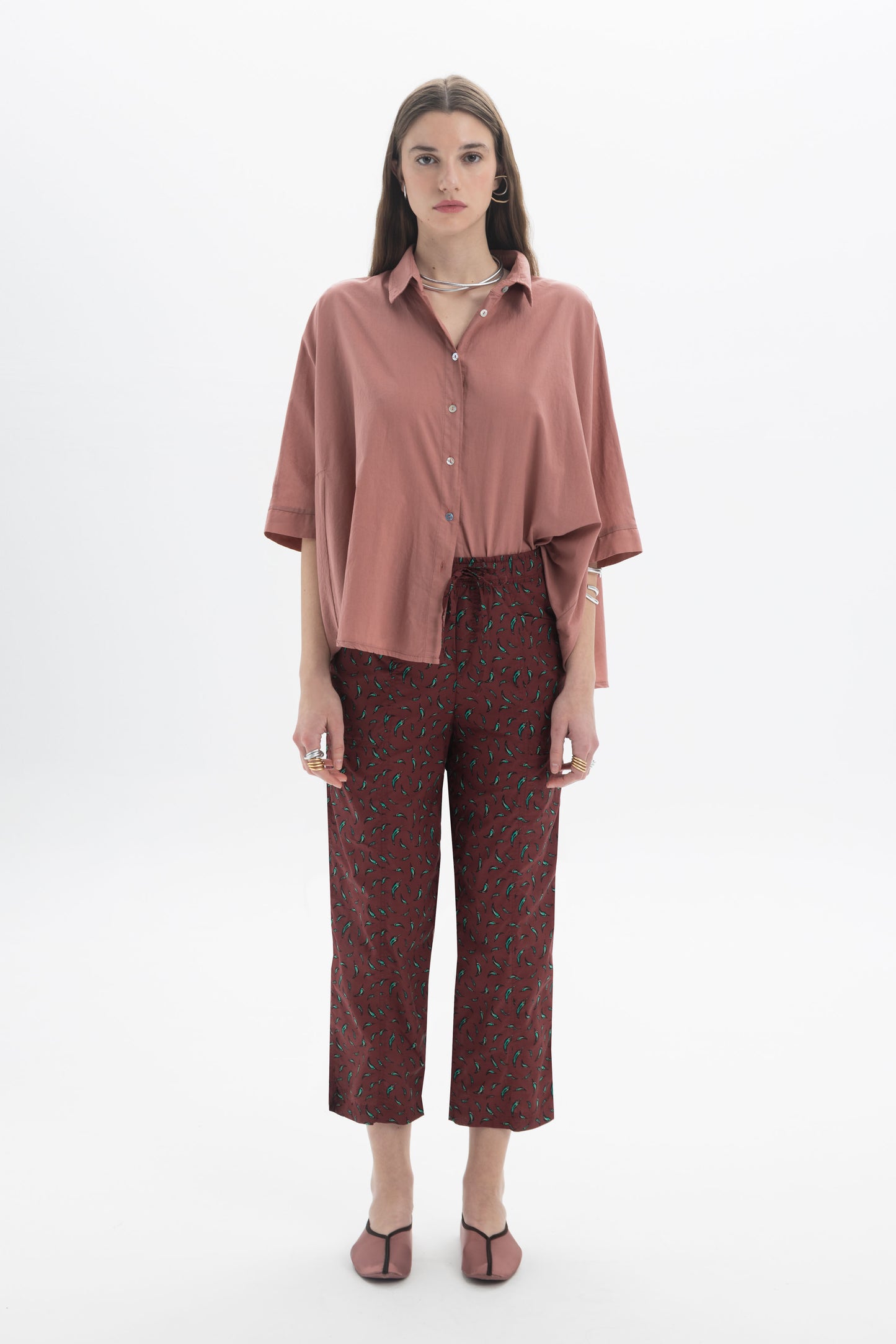 Model wearing Regular Fit Cropped Pants with a lightweight printed fabric and a relaxed fit, styled with a pink shirt.