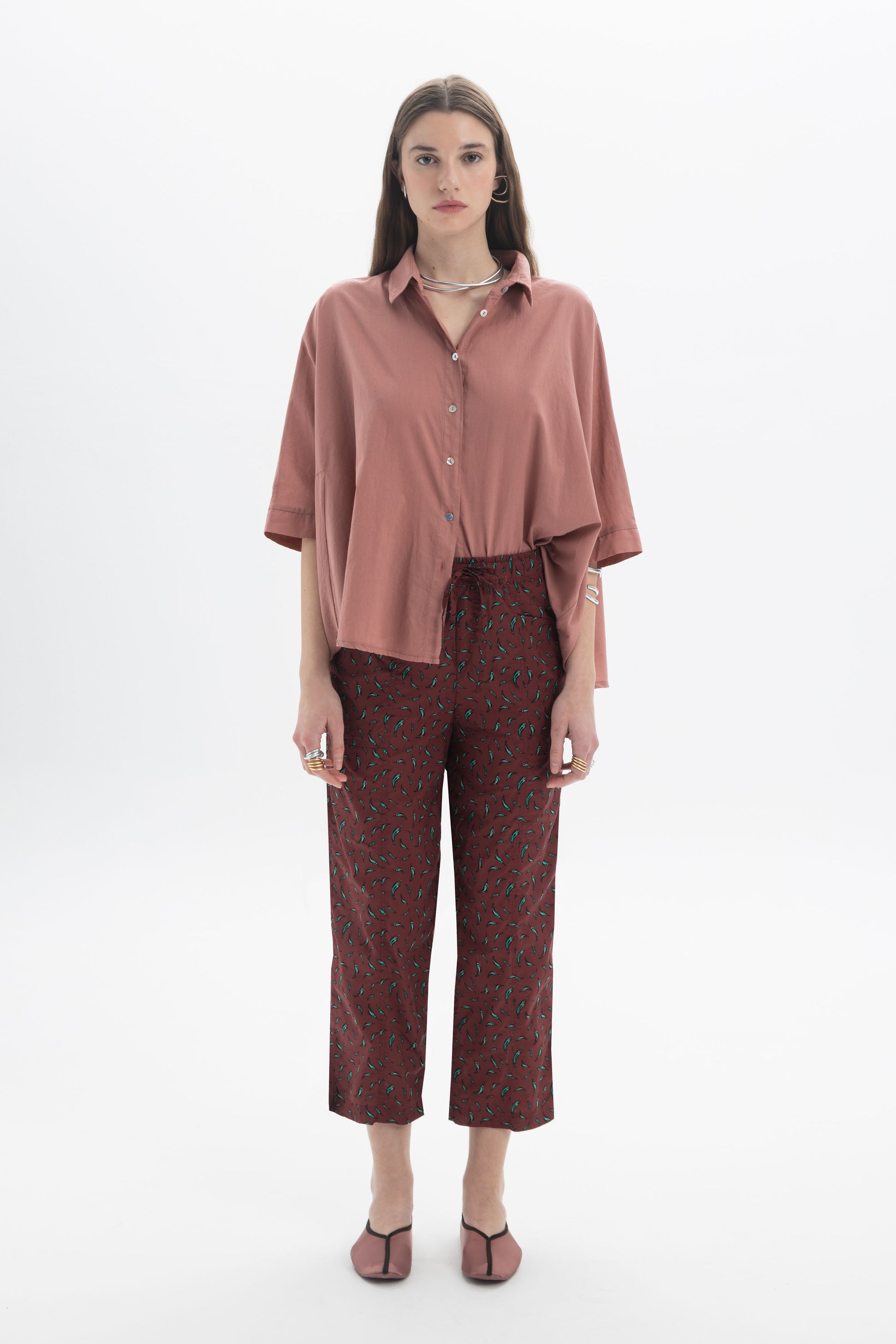 Model wearing Regular Fit Cropped Pants with a lightweight printed fabric and a relaxed fit, styled with a pink shirt.