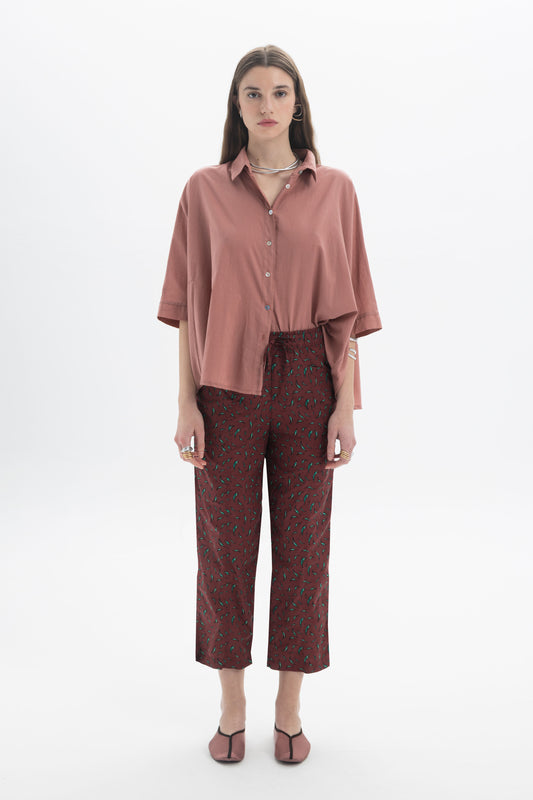 Model wearing Regular Fit Cropped Pants with a lightweight printed fabric and a relaxed fit, styled with a pink shirt.