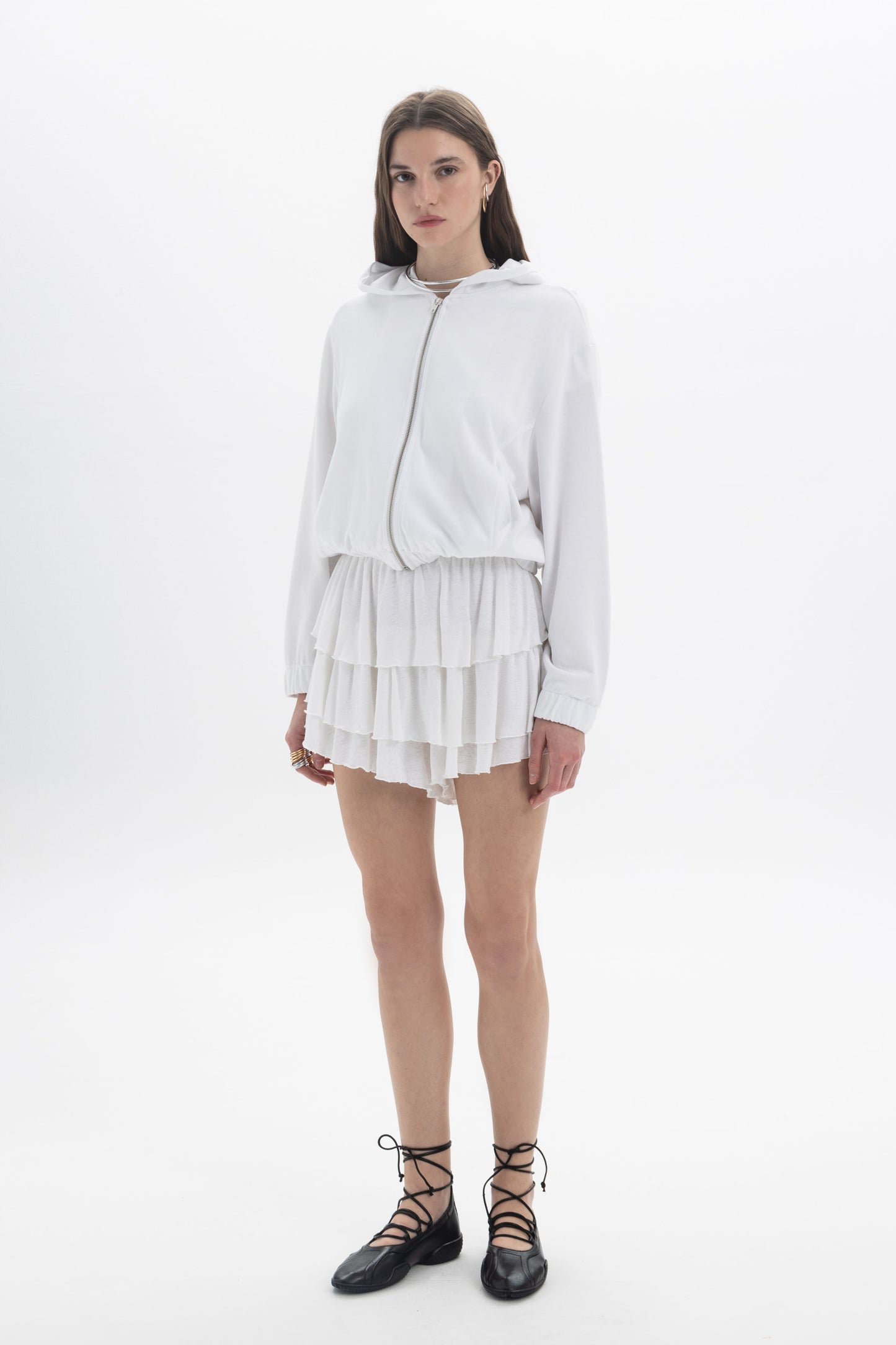 Model wearing B&B x F Layered Ruffle Shorts with a white zip-up hoodie and lace-up shoes.
