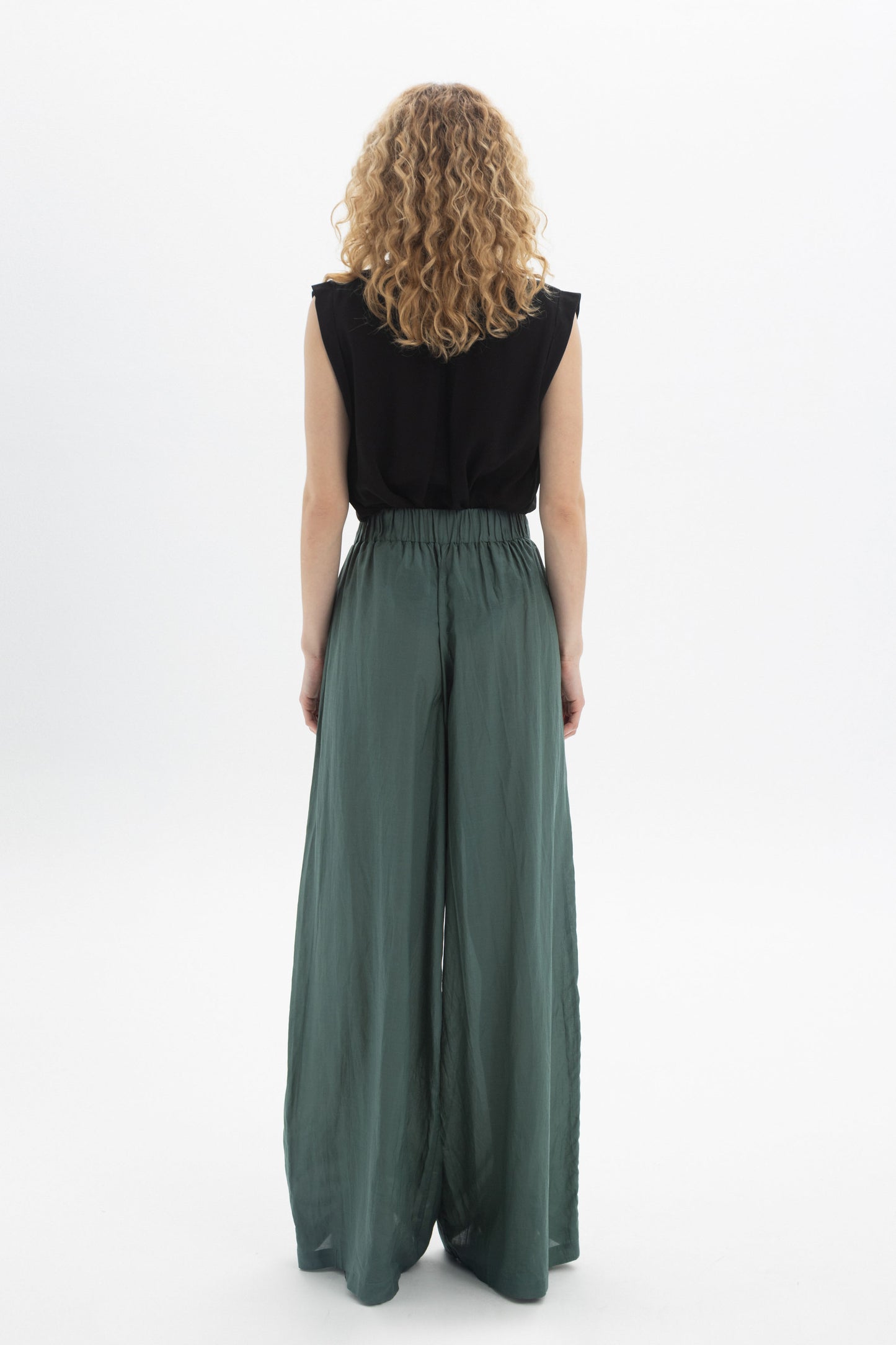 Woman wearing Wide-Leg Belted Pants in green from the back, showcasing high waist and flowing style.