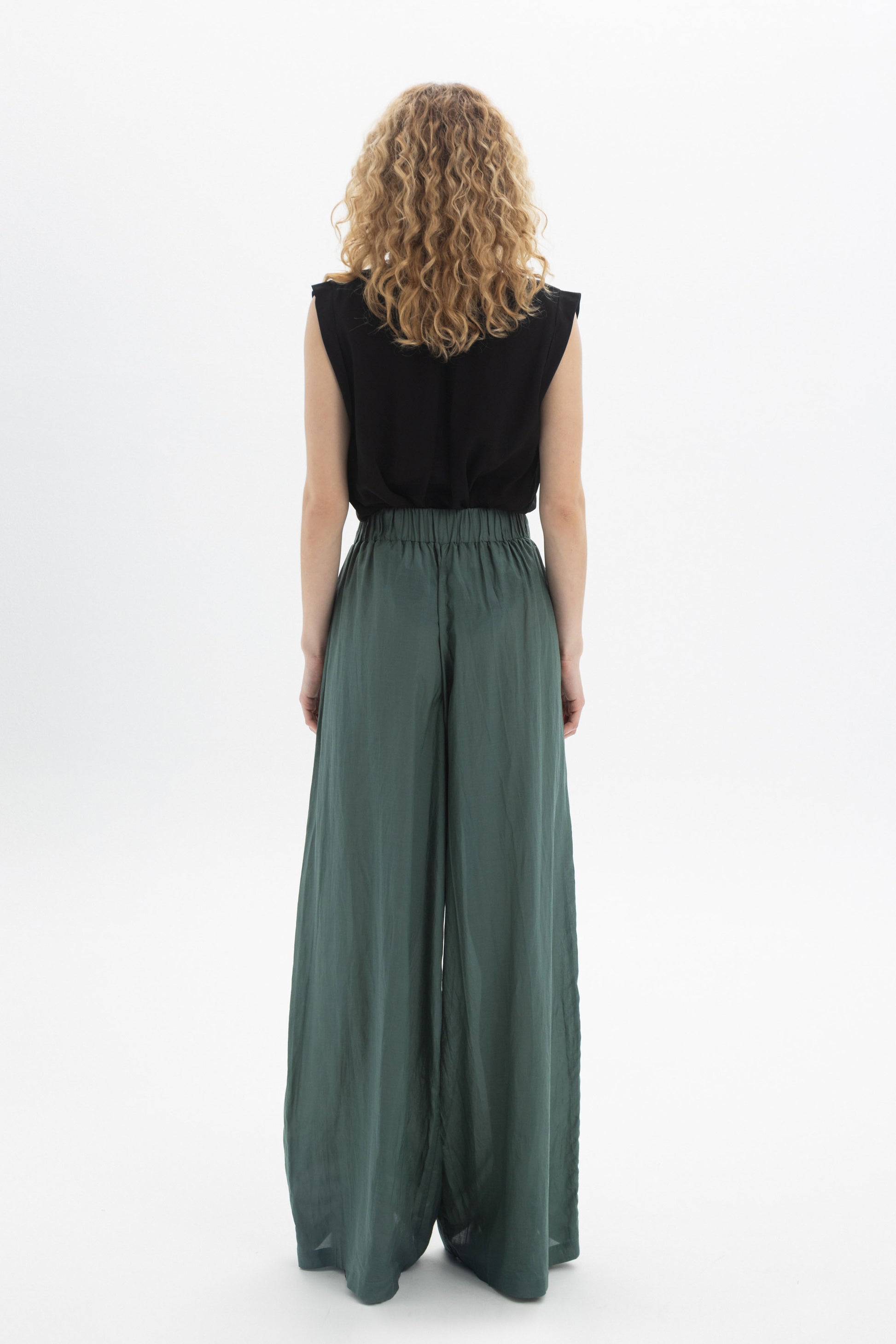 Woman wearing Wide-Leg Belted Pants in green from the back, showcasing high waist and flowing style.